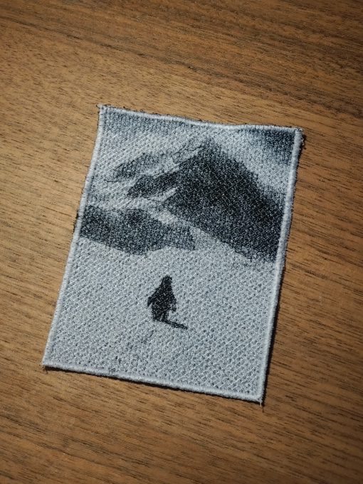 Penguin silhouette in front of a mountain landscape as a fine grayscale embroidery patch, 10x8 cm
